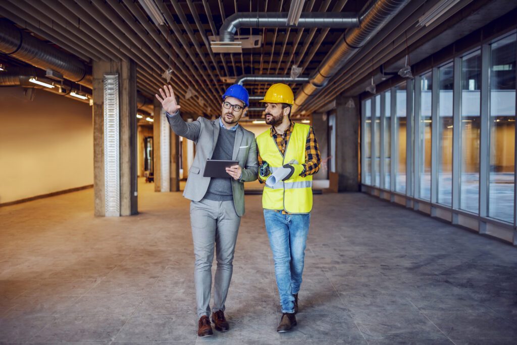 Architect holding tablet and explaining his ideas to construction worker